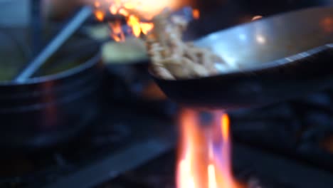 Flipping-Meat-Pieces-In-Pan-On-Gas-Stove-With-Bright-Orange-Flames