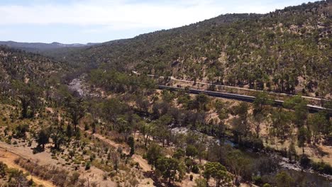 Rise-Up-Aerial-View-Of-Indian-Pacific-Passenger-Train-Leaving-Through-Perth-Hills