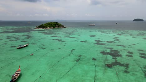 Aerial-Rising-Shot-Over-Moored-Traditional-Longtail-Fishing-Boats-In-Waters-In-Koh-Lipe-With-Reveal-Out-To-Open-Sea