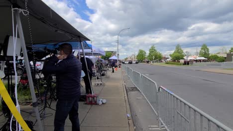 POV-Walking-Behind-TV-News-Crews-Beside-Railings-Reporting-On-The-Mass-race-shooting-in-Buffalo,-New-York-On-17-May-2022