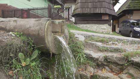Small-manmade-wooden-waterfall-on-the-countryside-surrounded-by-traditional-homes-in-traditional-village-Vlkolinec,-Slovakia