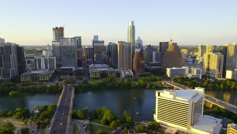 Aerial-view-overlooking-the-river-and-the-sunlit-skyline-of-Austin,-USA---tracking,-drone-shot