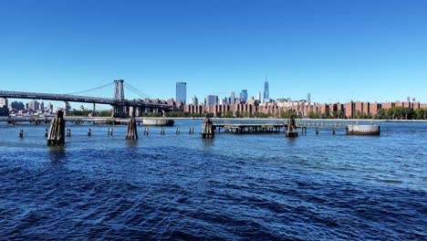 New-York-City-North-Williamsburg-Pier-with-a-view-of-East-River,-Williamsburg-Bridge-and-the-skyline-of-Manhattan-with-One-World-Trade-Center-on-a-clear-and-sunny-summer-day