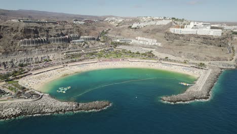 Aerial-view-of-the-tourist-resort,-famous-Amadores-beach-with-white-sand-surrounded-by-cliffs