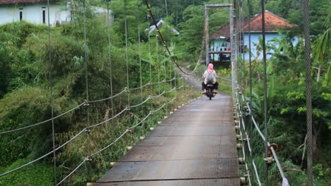 Puente-Colgante-Sobre-El-Río-Con-Cruce-De-Motocicletas-Por-La-Mañana-En-Sukabumi,-Java-Occidental,-Indonesia-El-4-De-Mayo-De-2022