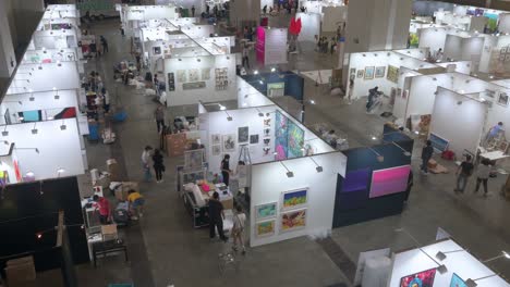 View-from-above-of-art-exhibitors-preparing-ahead-for-the-opening-of-a-contemporary-art-fair-as-they-set-up-and-decorate-the-booths-and-hang-the-painting-for-sale-during-the-installation-day