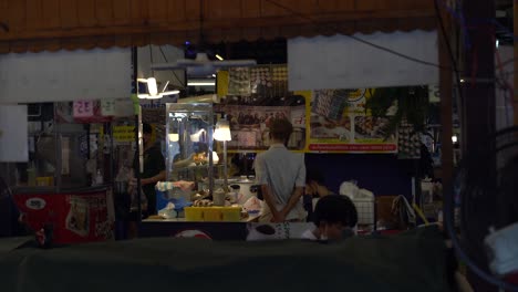 Man-at-food-stall-at-night,-street-of-Bangkok