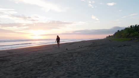 Young-woman-coming-back-from-the-warm-south-pacific-ocean-during-sunset-and-walking-towards-the-camera-in-slow-motion