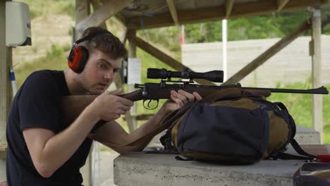 Side-Portrait-Of-A-Caucasian-Man-Wearing-Earmuffs,-Aiming-At-Target-Using-Shotgun-With-Optics-Mount-At-The-Shooting-Range