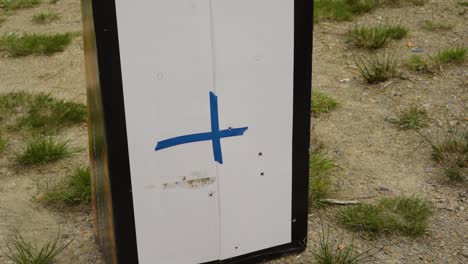 Blue-Cross-Mark-On-A-Target-Object-Standing-In-An-Outdoor-Firing-Range