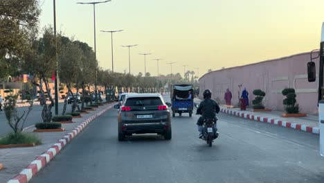 Fahren-Auf-Einer-Stark-Befahrenen-Straße-Bei-Sonnenuntergang-In-Der-Stadt-Marokko-Mit-Fahrrad,-Auto-Und-Bus