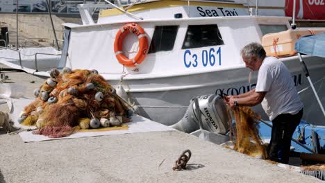 Mann-Repariert-Orangefarbene-Fischernetze-Auf-Einem-Festgemachten-Boot-Im-Hafen-Von-Sozopol