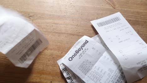 Falling-receipts-and-hand-placing-coins-on-the-pile-of-receipts-UK-cost-of-living-crisis