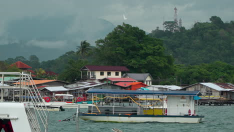 Many-Hopping-Tour-Boats-Moored-at-Kampung-Tanjung-Aru-Lama-Bay-Coastline,-Water-Village-Houses-in-Backgound-In-Sabah,-Kota-Kinabalu