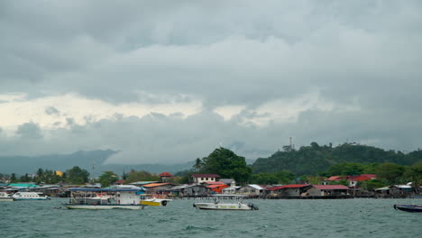 Tourist-Boats-Floating-Moored-by-Kampung-Tanjung-Aru-Lama-District-Coastline,-Kota-Kinabalu-Mountain-Hidden-Behind-Dense-Clouds,-Malaysian-Water-Village