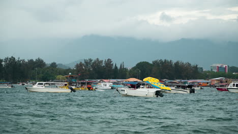 Speed-Boats-Moored-Near-Old-Wooden-Houses-on-Water-in-Bay-Area-of-Kampung-Tanjung-Aru-Lama-,-Kinabalu-Mount-Behind