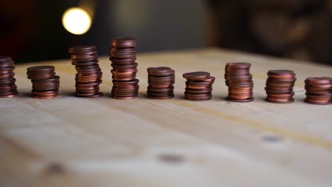 Many-small-cent-coins-stacks-lined-up-in-a-row-on-a-wooden-board-rotate-against-a-dark-background