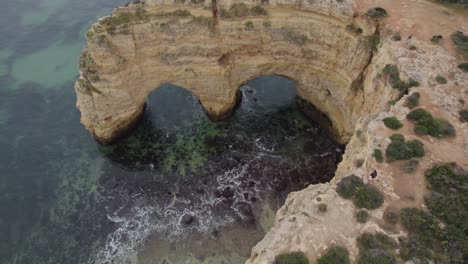 Aerial-view-Benagil-caves-rock-formation-arches-in-Algarve-Portugal-and-scenic-ocean-shoreline