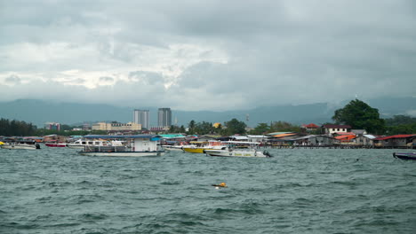 Kampung-Tanjung-Aru-Lama-Marina-Bay-Con-Muchos-Barcos-Flotantes-Amarrados-Cerca-De-Casas-De-Gente-Pobre-Construida-Sobre-El-Agua-En-Kota-Kinabalu,-Malasia