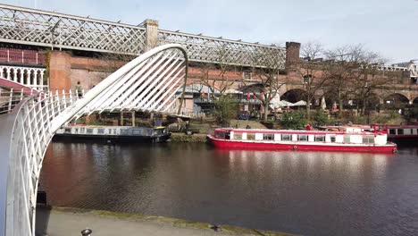 Manchester-Castlefields-canal-basin-located-near-the-Deansgate-area-of-Manchester,-UK-and-showing-modern-against-old-architecture-as-well-as-traditional-barges-on-the-canal-quayside