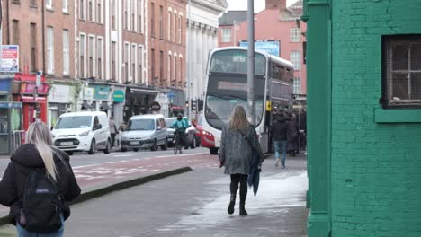 Arbeitstag-Auf-Der-Washington-Street-In-Cork-City-Mit-Weiblichen-Fußgängern,-Einem-Fahrradlieferanten-Und-Einem-Bus-An-Einer-Bushaltestelle