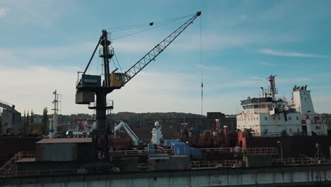 Drone-flying-around-crane-while-loading-cargo-ship-in-shipyard
