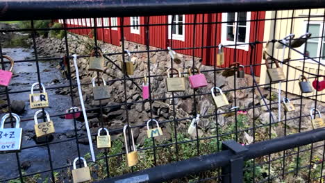Love-locks-on-a-brige-fence-with-a-dryed-out-stone-canal,-and-old-buildings-on-each-side-in-the-background