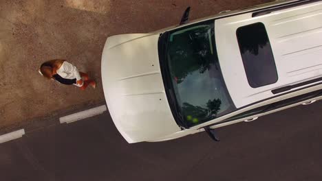 4k-aerial-shot-of-a-stranded-young-woman-looking-under-the-hood-of-her-broken-down-car