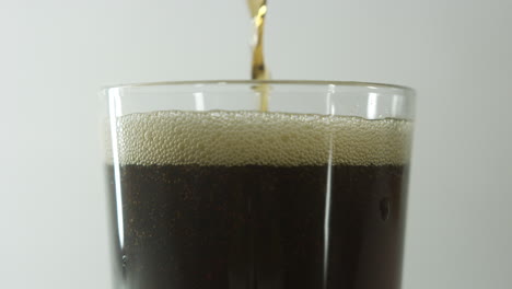 Cola-Wird-In-Ein-Glas-Gegossen,-Wobei-Nur-Der-Obere-Teil-Des-Glases-Vor-Einem-Hellen,-Schlichten-Hintergrund-Sichtbar-Ist