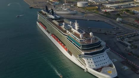 Aerial-overview-of-the-big-cruise-ship-in-dock-with-small-ships-sailing-in-the-marina