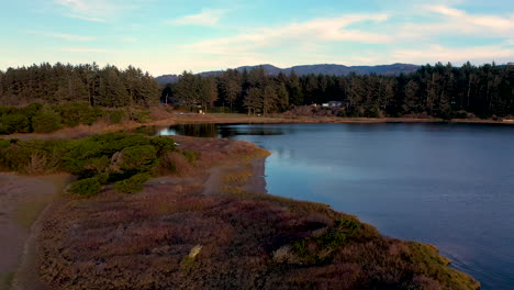 Drone-descending-on-shore-of-Floras-Lake,-Southern-Oregon,-USA