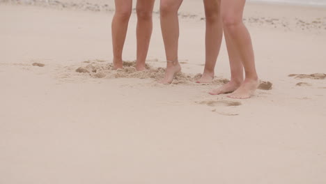 Mittlere-Aufnahme-Der-Beine-Kaukasischer-Mädchen,-Die-Sich-Während-Eines-Fotoshootings-Im-Sand-Eines-Strandes-Bei-Tageslicht-Bewegen