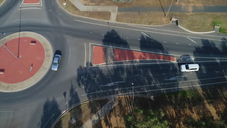 Aerial-topdown-of-cars-driving-through-roundabout-during-morning-sunlight-in-a-rural-city-in-Australia
