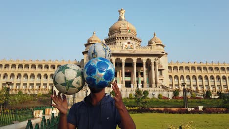 Un-Artista-Que-Realiza-Trucos-Con-Balones-De-Fútbol-Frente-Al-Edificio-Vidhana-Soudha-En-Bengaluru,-Karnataka,-India,-Durante-La-Madrugada