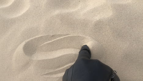 Shot-of-a-black-glove-drawing-waves-in-sand