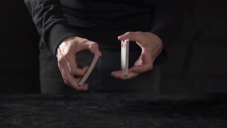 MCU-SLOW-MOTION:-Male-croupier-splits-a-deck-of-cards-in-half-and-performs-riffle-shuffle-on-a-black-table