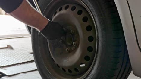 Removing-a-cars-wheel-nuts-with-a-air-gun-in-a-garage-workshop-on-hydraulic-lift