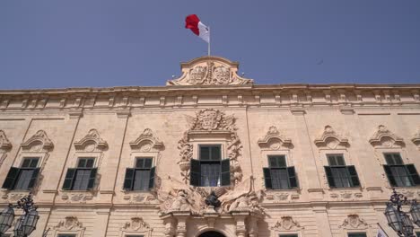 Auberge-De-Castilla-En-Valletta,-Malta-Empujar-Gimbal-Dolly-Shot-Con-Bandera-Ondeando-Y-Pájaro-Volando