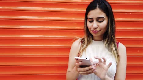 Slow-motion:Beautiful-young-girl-uses-smartphone-in-front-of-orange,red-background