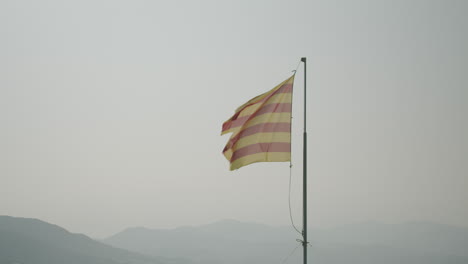 Bandera-Catalana-Ondeando-En-El-Viento-En-El-Port-De-La-Selva-Y-Montañas-En-El-Fondo