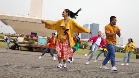 A-group-a-young-teenagers-and-youth-dancing-together-with-the-large-Monas-Monument-behind-them