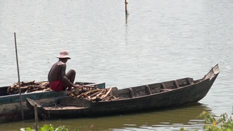 Man-Sorting-Firewood-in-Boat