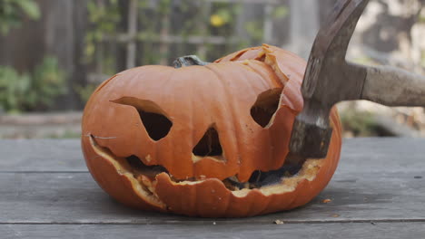 Slow-motion-close-up-of-a-rotten-jack-o-lantern-being-smashed-with-a-hammer