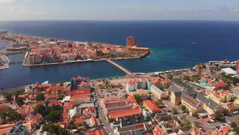 Drone-footage-in-Sint-Anna-Bay-with-the-pontoon-bridge-of-Queen-Emma-in-the-foreground-in-Willemstad,-Curacao