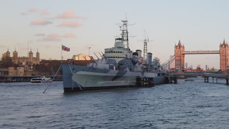View-of-a-military-ship-in-front-of-London-tower-and-bridge-at-sunset-over-Thames-river