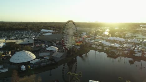 Aerial-View-of-Ferris-Wheel-at-Florida-State-Fair-During-Sunset-With-Tampa-Skyline-in-Far-Distance