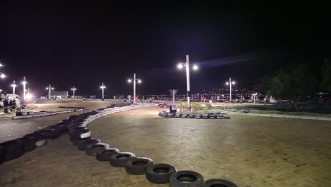 Go-carts-race-by-on-pavestone-night-course-in-Knysna,-South-Africa