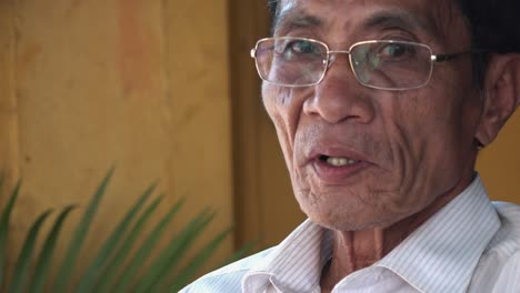 Close-Up-Shot-of-an-Elderly-Asian-Man-Smoking-a-Cigarette