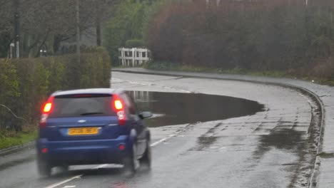 Vehicles-drive-around-dangerous-stormy-flash-flooded-road-corner-bend-UK