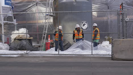 Construction-workers-working-together,-to-lay-out-a-plastic-tarp-in-Downtown-Denver,-Colorado